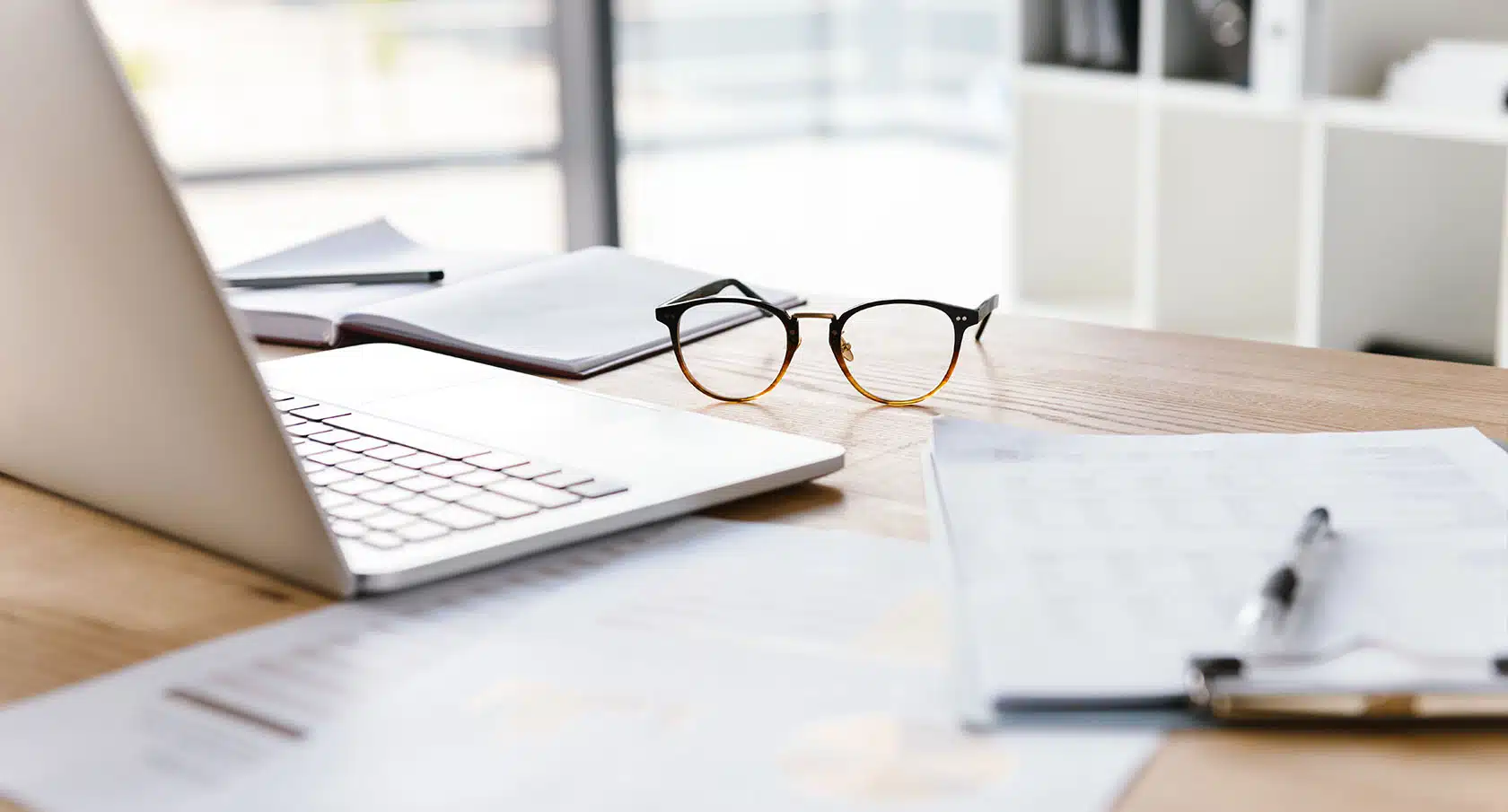 Kündigungsunterlagen, Stifte und eine Brille liegen auf einem Schreibtisch