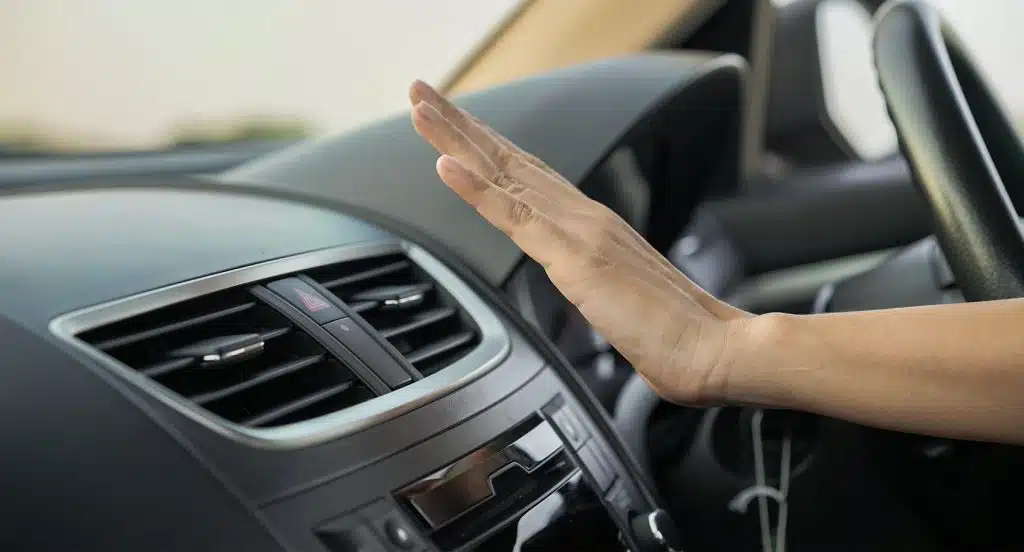 Eine Hand wird im Auto vor die Heizung gehalten