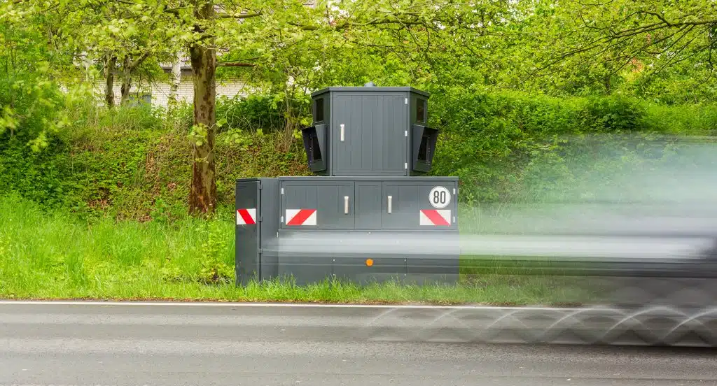 Versteckte Radarfalle vor einem Gebüsch